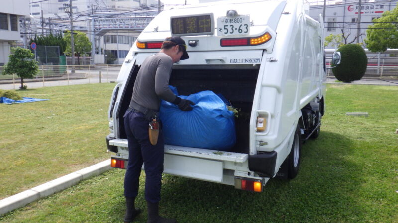 除草業者による草刈り後の雑草回収とトラックへの積み込み作業風景